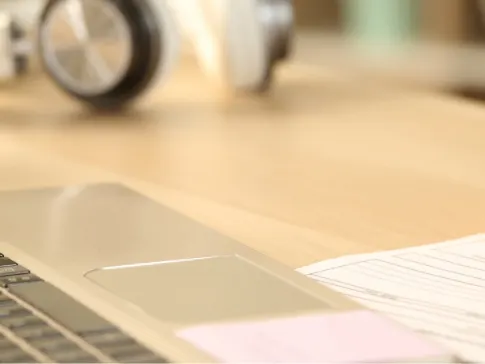 Stock photograph of a model: a hand holding a pen and filling in a printed form on a desk beside a laptop