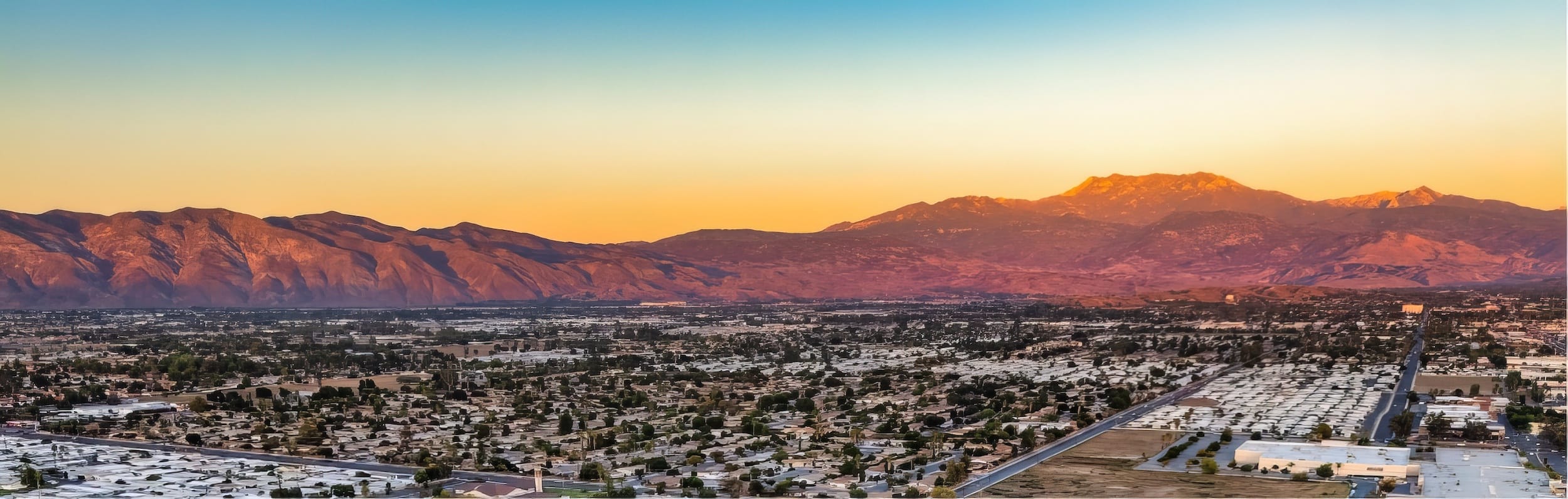 The Santa Clarita Valley at dusk, the town spread across the valley floor below a ridge of mountains